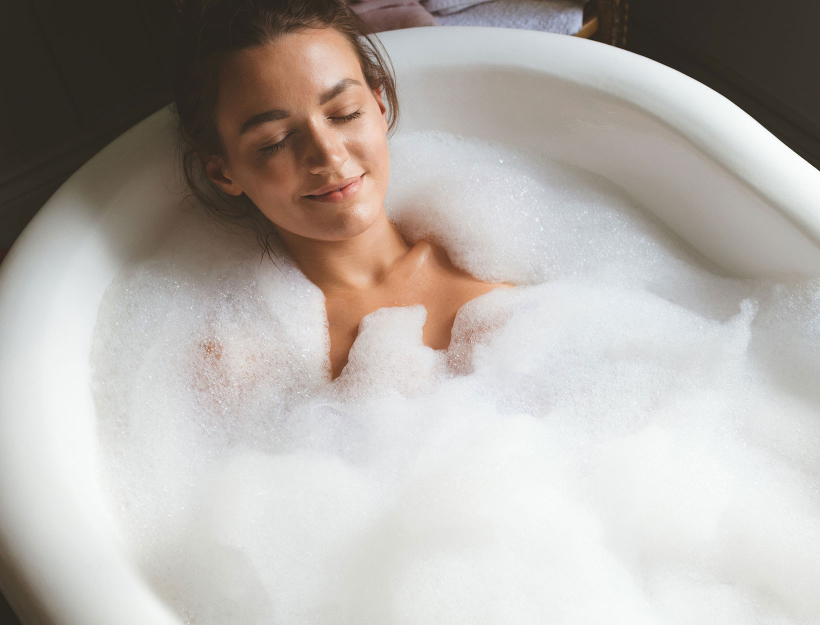 Woman taking a bubble bath in bathroom at home stock photo - OFFSET