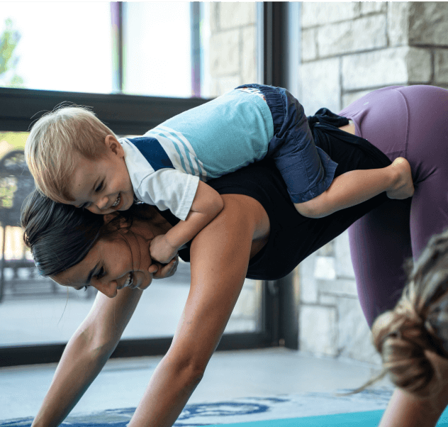 woman doing yoga with a child on her back